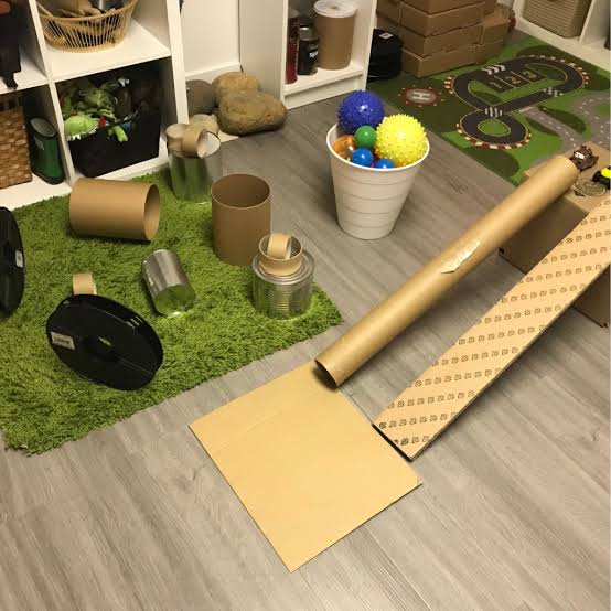Play space with cardboard tubes, ramps, tins and balls